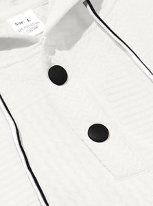 Detail of white textured hoodie showing black buttons and polyester blend fabric texture