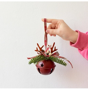 Detail of red metal Christmas bell with reindeer antlers and festive plaid ribbon