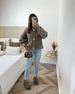 Détail d'un cardigan marron en grosse maille avec gros boutons dorés et poches plaquées