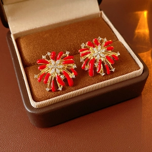 Macro detail of firework-inspired earrings with red enamel and crystals in a velvet box