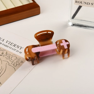 Close-up of tortoise shell hair claw clip with pink embossed details and spring mechanism