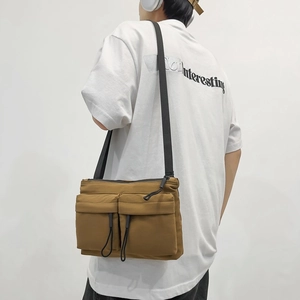 Brown nylon crossbody messenger bag with dual utility pockets and black shoulder strap