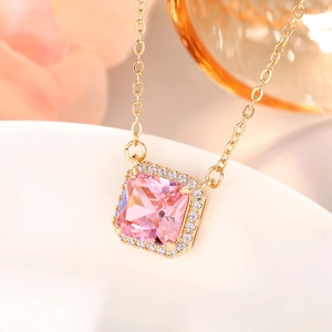 Macro shot of square pink gemstone pendant necklace with gold chain and diamond halo