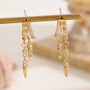 Macro shot of gold layered hoop earrings with dangling zircon fringe and metal spikes