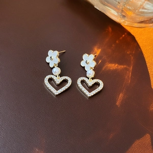 Detail of gold-plated flower heart earrings with pearls and zircon on leather