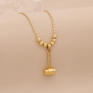 Vue macro du collier avec pendentif marteau doré et strass sur une chaîne à billes rondes