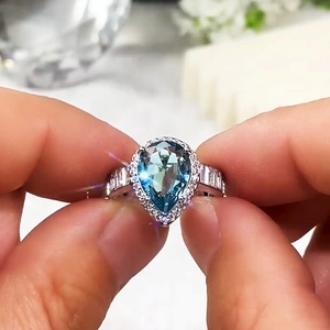 Macro detail of pear-shaped blue gemstone ring with halo diamonds and baguette side stones