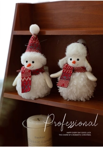 Detail of plush snowman ornaments with red knit hats on a rustic wooden shelf