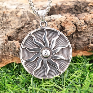Detail view of silver stainless steel sunburst pendant on rustic natural wood bark texture