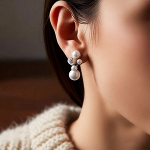 Detailed view of elegant pearl cluster earrings worn by model in a warm indoor setting
