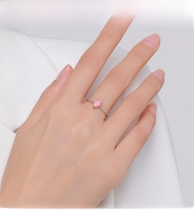 Close-up of pink teardrop opal gemstone on a golden chain link silver ring