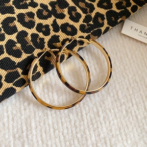 Macro shot of gold hoop earrings with leopard print inlay on white soft faux fur