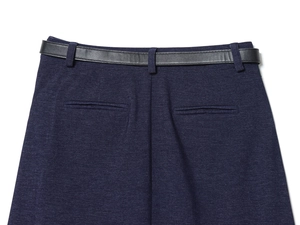 Dettaglio della gonna a pieghe blu navy con cintura in pelle nera e trama in twill rifinita