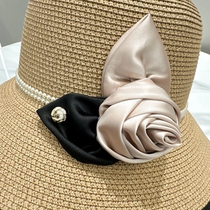 Détail du chapeau de paille vintage avec fleur en satin et bordure en perles fantaisie