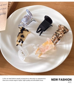 Detailed close-up of six patterned acetate mini hair claws on a ceramic plate