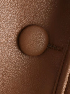 Détail de la veste en cuir marron avec texture de grain de litchi et boutons recouverts