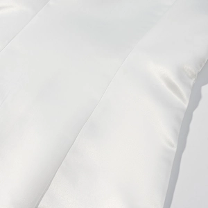 Close-up of white silk satin fabric texture and stitching details of the mini dress