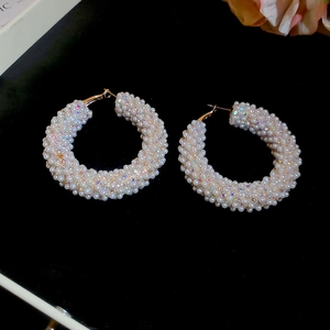 Detail of large hoop earrings with white pearls and sparkling rhinestones on velvet background