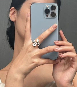 Detailed view of snake-shaped gold-plated ring with white and black enamel dots pattern