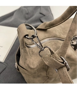 Detail shot of the polished silver lobster clasp on a khaki suede oversized travel bag