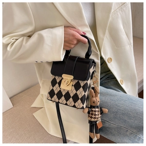 Detail of checkered handbag with gold lock and cute bunny doll charm accessory