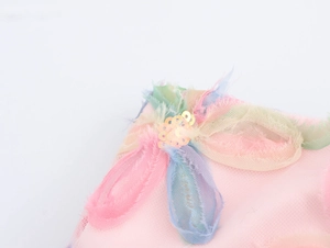 Detailansicht eines rosa Netzrocks mit bunten 3D-Blumen und goldenen Pailletten