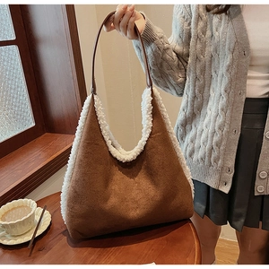 Detail view of brown faux suede tote bag with white faux fur trim and leather handles