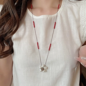 Close-up of white pearl flower pendant with brown bead center on a cord necklace