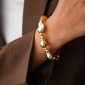 Detail of vintage acrylic beaded bracelet with irregular gold geometric metal charms