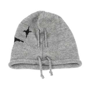 Detail of grey knitted beanie featuring black star pattern and adjustable drawstrings
