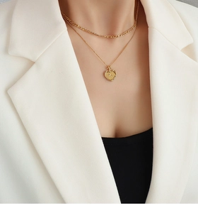 Détail d'un collier double épaisseur doré avec pendentif cœur scintillant sur un mannequin