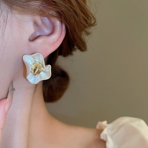 Macro detail of a cream floral stud earring with gold center on model's ear