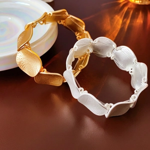 Textured gold and silver interlocking leaf bangle bracelets in a minimalist luxury design