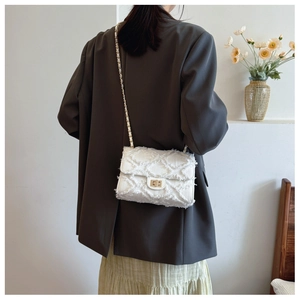 Detail of white fringed chain bag showing wave-edge texture and gold swivel lock