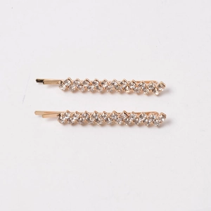 Detail of two gold-toned hair clips featuring a single row of sparkling clear rhinestones