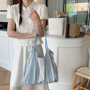 Detail of floral tote bag showing fabric texture and blue striped stitching on front