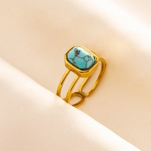 Detail of adjustable gold ring featuring a rectangular turquoise stone on pink satin fabric