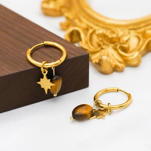 Detail of gold-plated star and oval tiger eye stone charms on hoop earrings