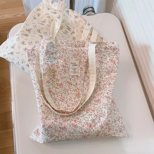 Close-up of floral canvas tote bag showing pink flower patterns and textile label