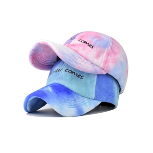 Detail of plush tie-dye baseball caps with Winter Comes embroidery in pink and blue