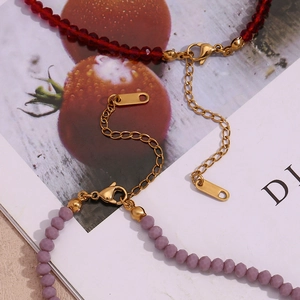 Detailed shot of red faceted crystal and purple beads on a gold chain with lobster clasp