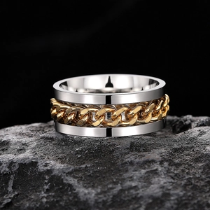 Detail of a men's silver and gold rotating chain ring on a textured dark rock