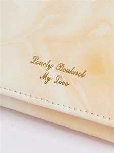 Detailed macro view of beige marble textured leather wallet with gold Lovely Bowknot text