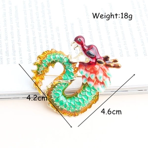 Golden dragon brooch with red and green enamel on a magazine background, 4.2cm x 4.6cm
