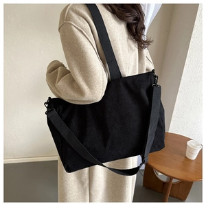 Detail of black corduroy tote bag showing ribbed texture and adjustable crossbody strap