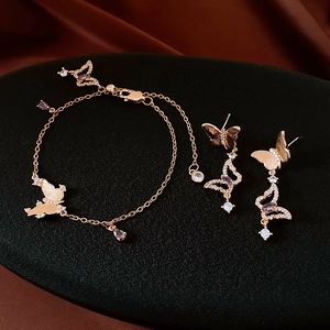 Detail of gold butterfly jewelry set featuring purple zircon pendants on silk