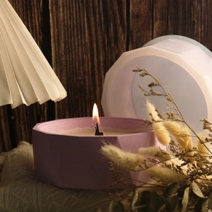 Dettaglio di un vasetto di candela geometrico viola con coperchio in una calda cornice di casa