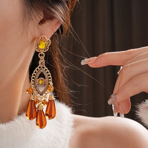 Detail of vintage gold tassel earring with amber teardrop gemstone on a model
