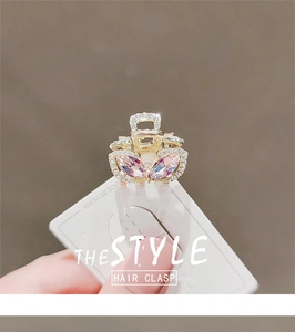 Macro shot of gold-plated rabbit ear hair clip with pink rhinestones on white card