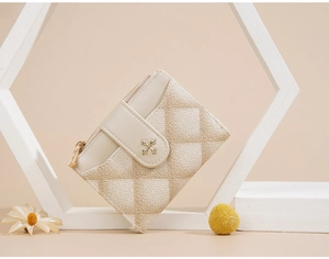Detail of beige quilted PU leather wallet featuring cross charm buckle and zip closure